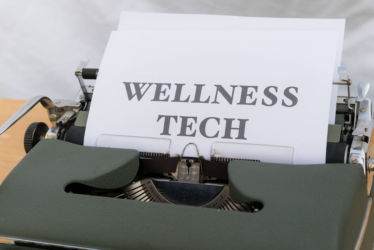 A close-up of a vintage typewriter featuring a paper with the words Wellness Tech.